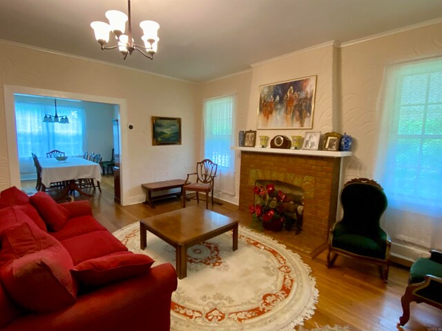 living room featuring a notable chandelier, a brick fireplace, hardwood / wood-style floors, and ornamental molding