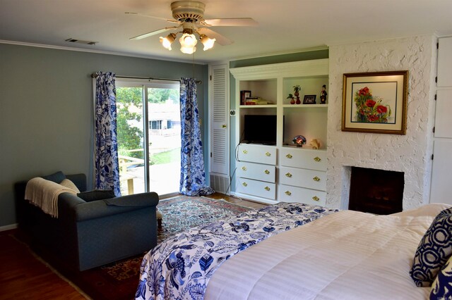 bedroom featuring ceiling fan, a large fireplace, hardwood / wood-style flooring, and access to exterior