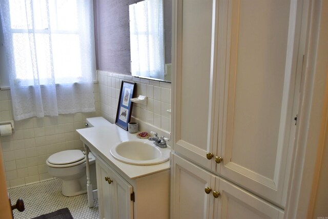 bathroom featuring tile walls, vanity with extensive cabinet space, toilet, tasteful backsplash, and tile flooring