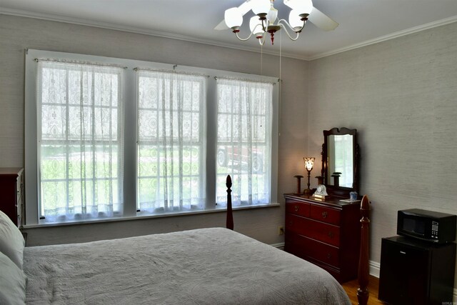 bedroom featuring dark wood-type flooring, crown molding, and ceiling fan with notable chandelier