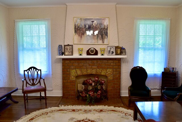 sitting room featuring a healthy amount of sunlight, ornamental molding, dark wood-type flooring, and a brick fireplace