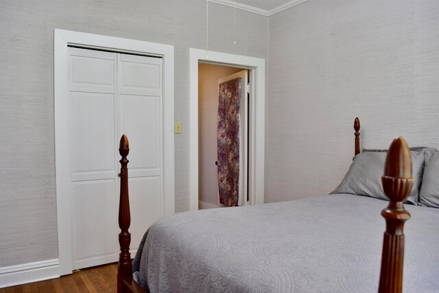 bedroom with a closet, crown molding, and dark wood-type flooring