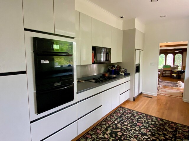 kitchen featuring black appliances, light hardwood / wood-style flooring, and gray cabinets