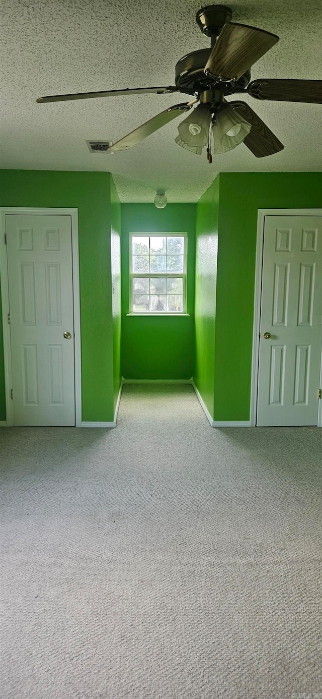 empty room featuring carpet, ceiling fan, and a textured ceiling