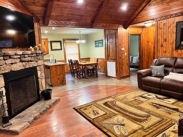 living room featuring wooden walls, light wood-type flooring, wood ceiling, sink, and a stone fireplace