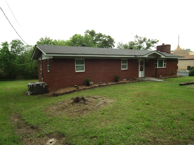 back of property featuring a lawn and central air condition unit