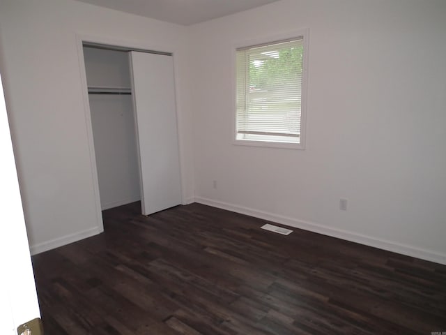 unfurnished bedroom featuring a closet and dark hardwood / wood-style floors