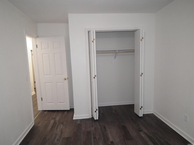 unfurnished bedroom with a closet and dark hardwood / wood-style floors