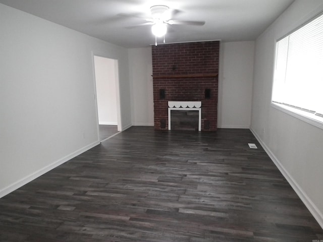 unfurnished living room featuring brick wall, dark hardwood / wood-style flooring, ceiling fan, and a fireplace