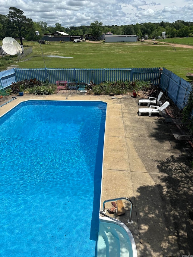 view of swimming pool featuring a patio and a yard