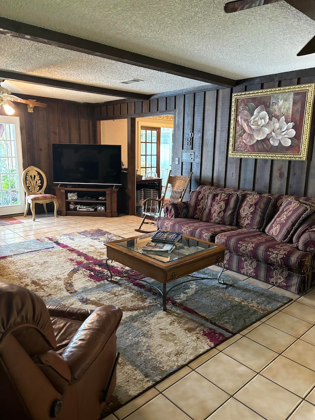 tiled living room featuring a textured ceiling, wood walls, and ceiling fan