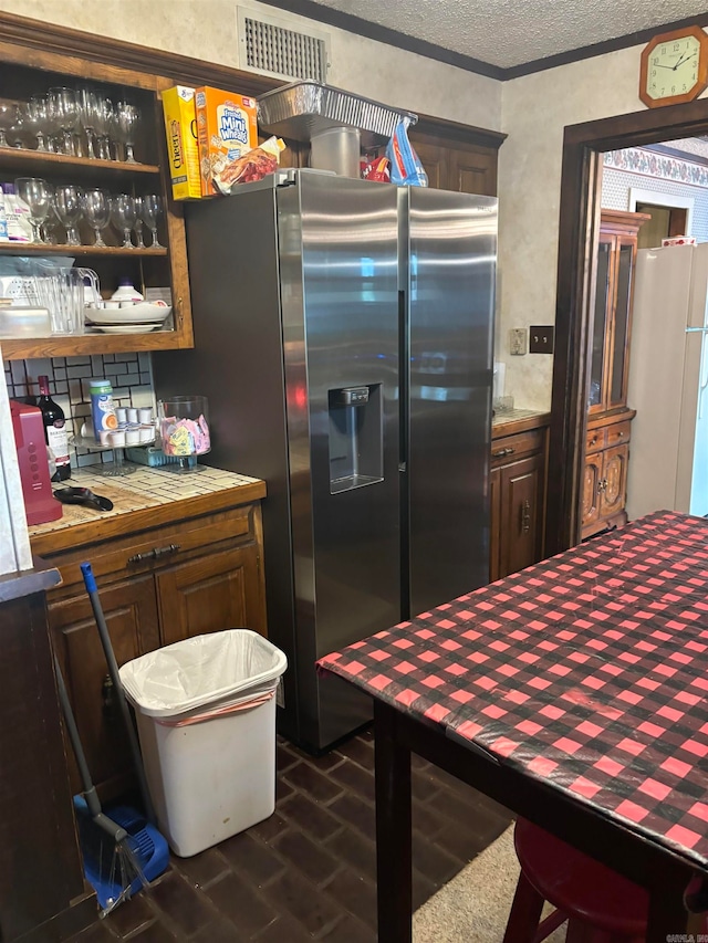 kitchen with white refrigerator, stainless steel fridge with ice dispenser, backsplash, and crown molding