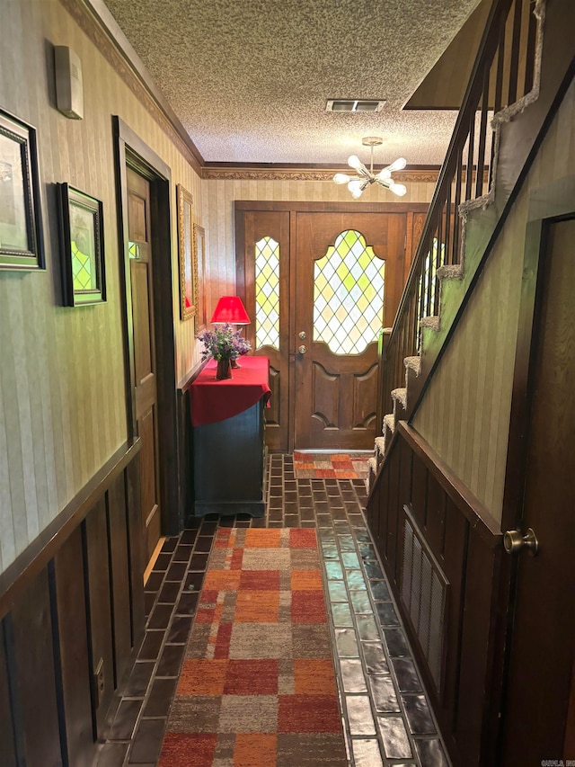 interior space featuring crown molding, an inviting chandelier, and a textured ceiling