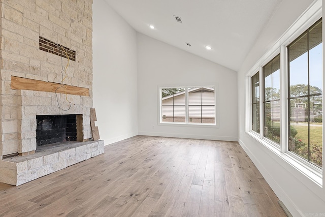 unfurnished living room featuring plenty of natural light, a stone fireplace, and light wood-type flooring