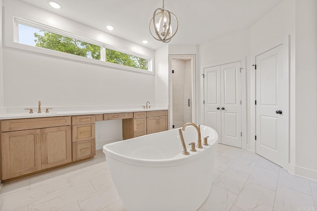 bathroom featuring an inviting chandelier, tile patterned floors, vanity, and a bathtub