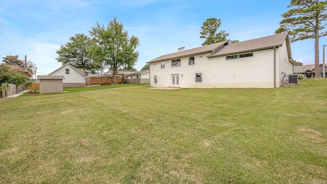 back of house featuring a storage shed, central AC, and a lawn