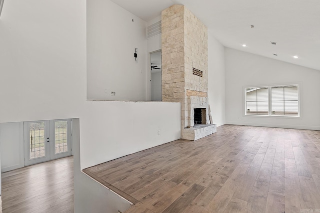 unfurnished living room featuring hardwood / wood-style floors, a fireplace, french doors, high vaulted ceiling, and ceiling fan