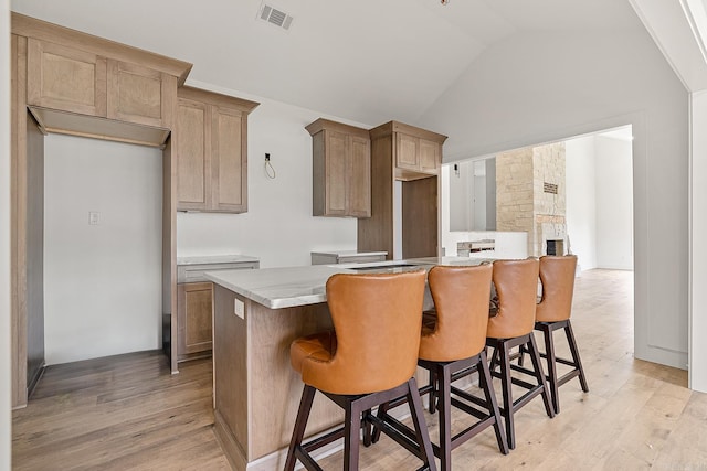 kitchen featuring light hardwood / wood-style floors, a kitchen breakfast bar, vaulted ceiling, and a center island