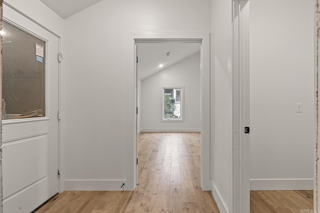 hall with lofted ceiling and light wood-type flooring