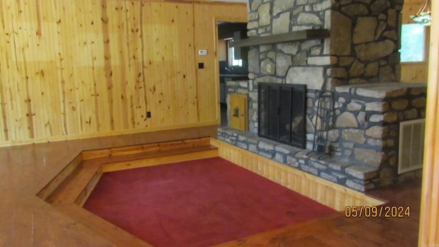 unfurnished living room featuring wood walls and a fireplace