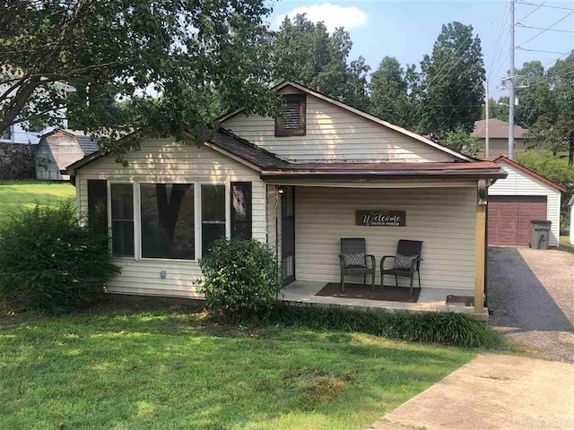 back of property with an outdoor structure, a yard, and a garage