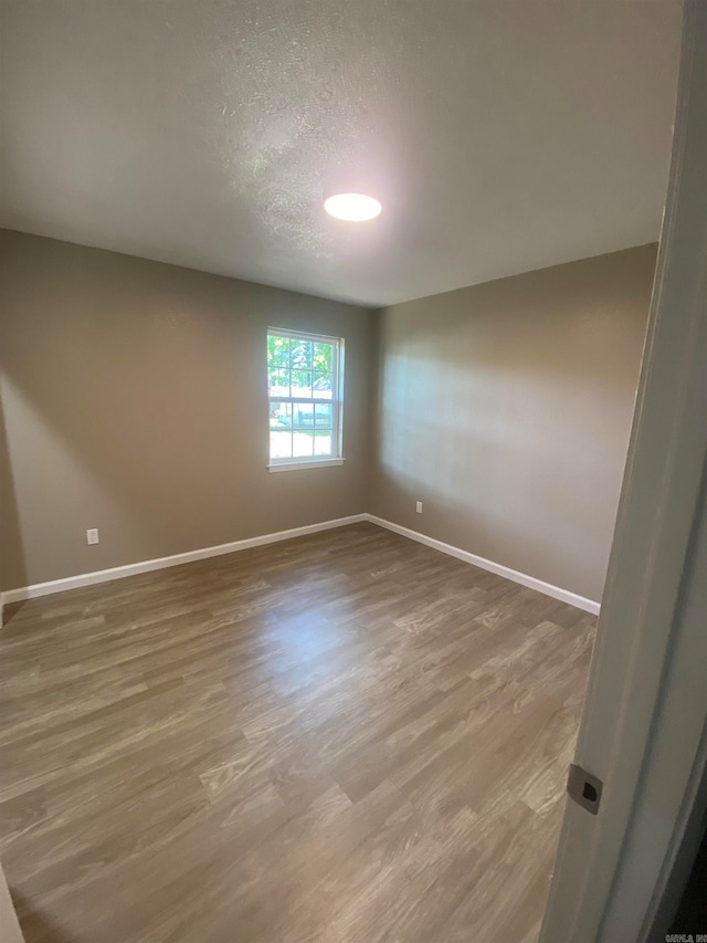 unfurnished room with a textured ceiling and hardwood / wood-style flooring