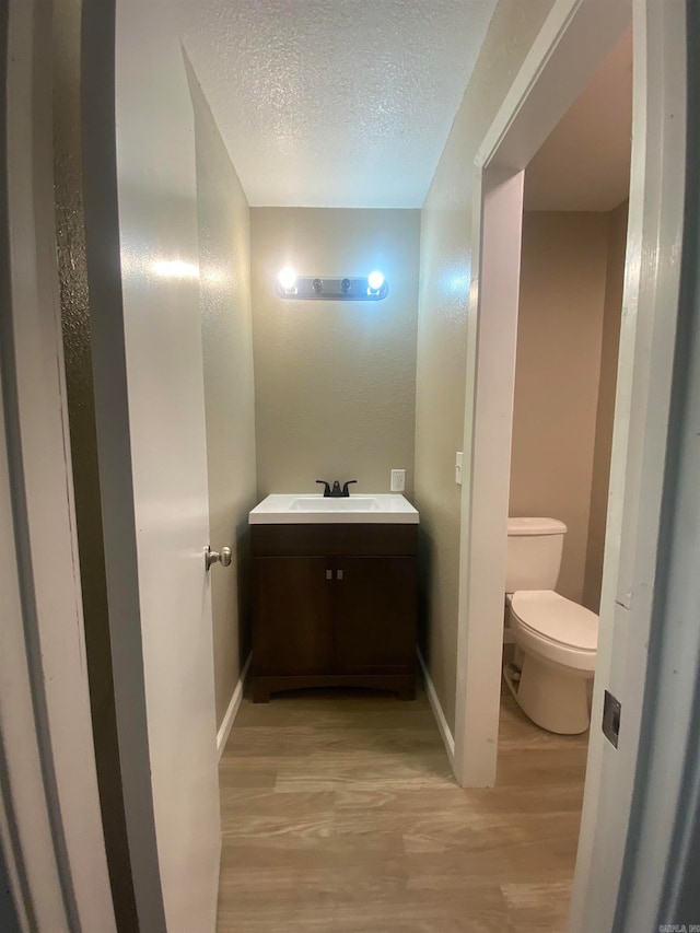 bathroom with vanity, toilet, a textured ceiling, and hardwood / wood-style flooring