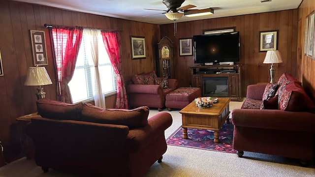 living room with ceiling fan, plenty of natural light, wooden walls, and carpet floors