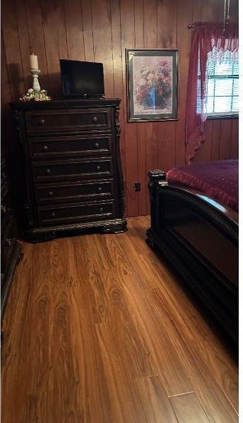 bedroom featuring wood-type flooring and wood walls