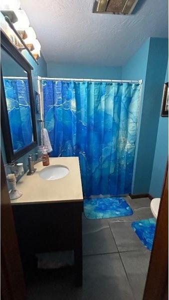 bathroom featuring vanity, toilet, tile patterned flooring, and a textured ceiling