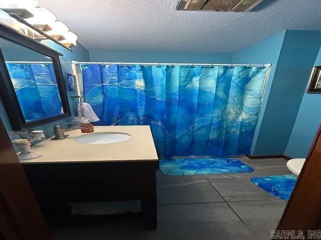 bathroom featuring vanity, tile patterned floors, a textured ceiling, and toilet