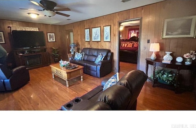 living room featuring hardwood / wood-style flooring, ceiling fan, and a fireplace