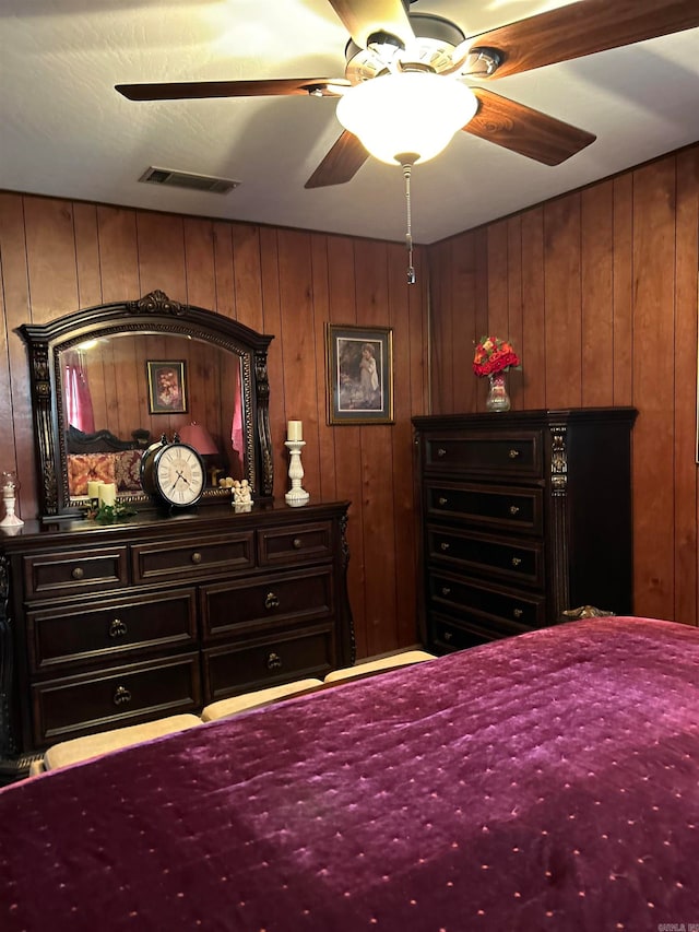 bedroom featuring ceiling fan and wood walls