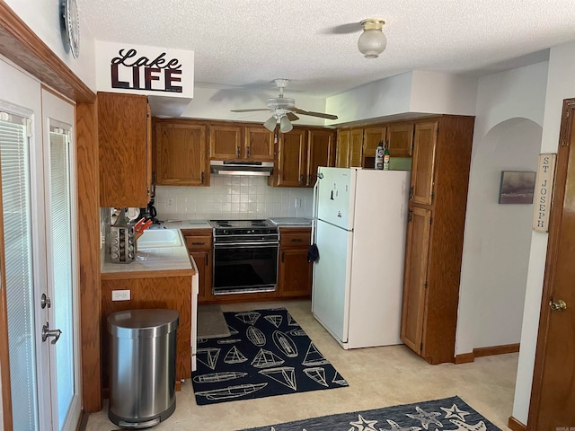 kitchen featuring ceiling fan, light tile floors, backsplash, white refrigerator, and electric range