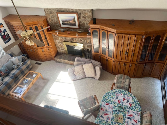 living room with a fireplace, ceiling fan, carpet, and a textured ceiling