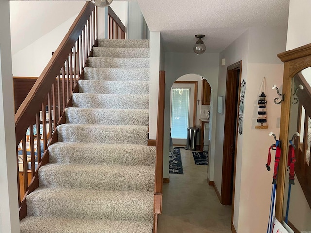 stairway with a textured ceiling and carpet floors