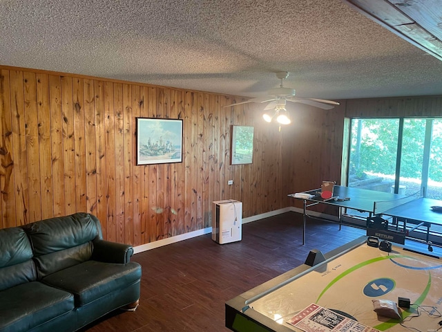 recreation room featuring dark hardwood / wood-style floors, ceiling fan, a textured ceiling, and wooden walls