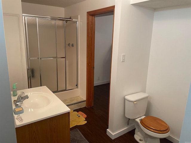 bathroom with wood-type flooring, vanity, toilet, and a shower with shower door