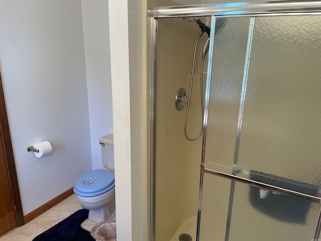 bathroom with tile flooring, toilet, and a shower with shower door