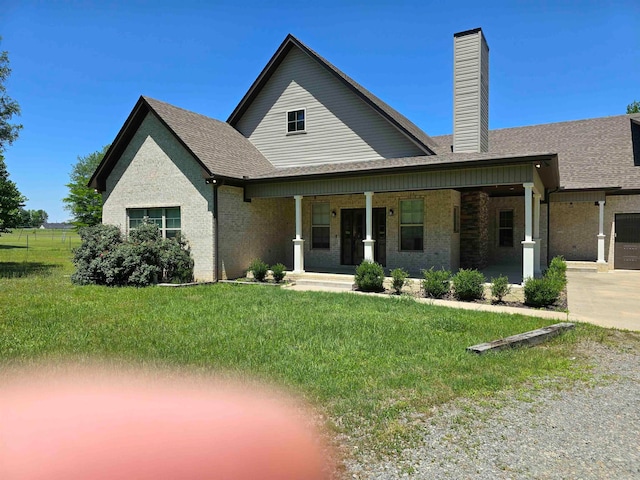 view of front of property featuring covered porch, a garage, and a front yard