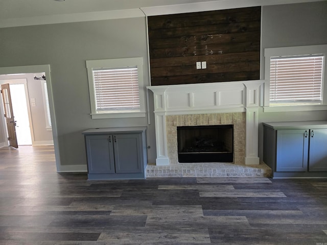 unfurnished living room with a healthy amount of sunlight, dark wood-type flooring, and a brick fireplace