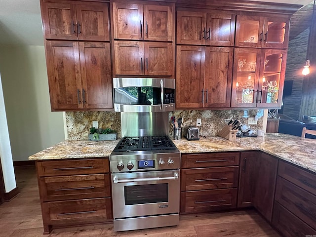 kitchen featuring wood-type flooring, tasteful backsplash, stainless steel appliances, and light stone counters