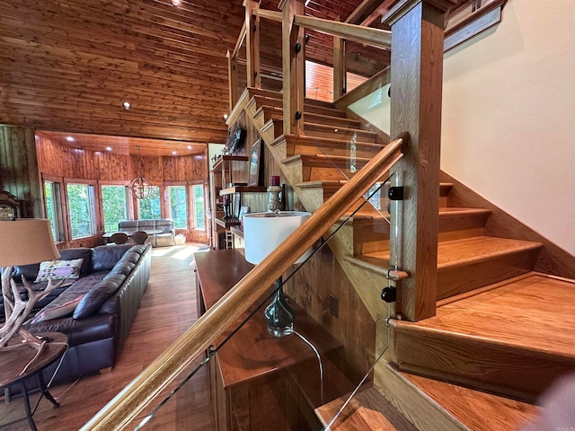 stairs with hardwood / wood-style floors, wood walls, and a high ceiling