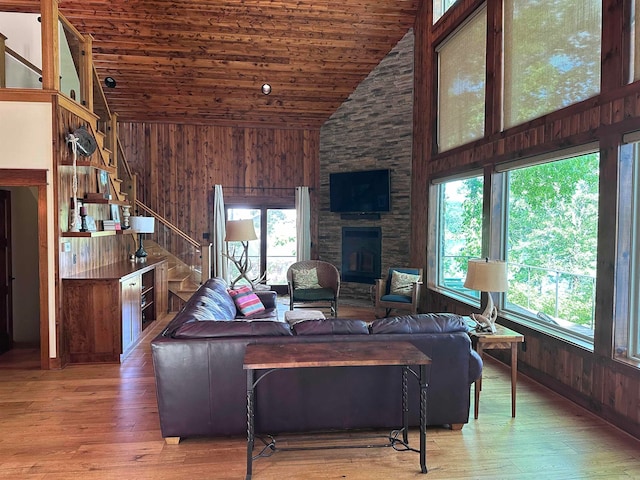 living room with wood-type flooring, a fireplace, wood ceiling, and wooden walls