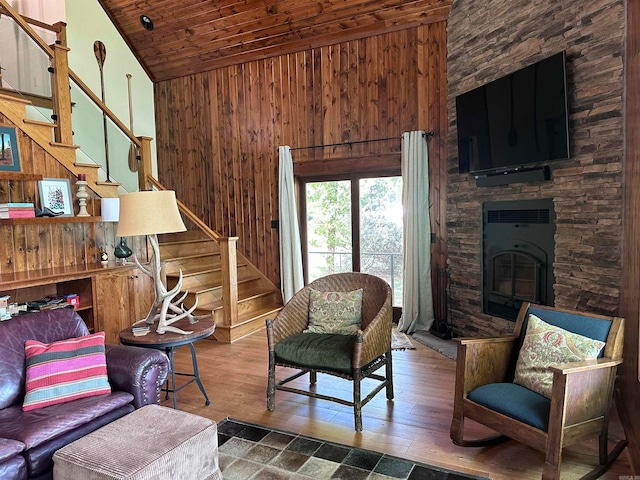 living room featuring wood ceiling, wood walls, a stone fireplace, and lofted ceiling
