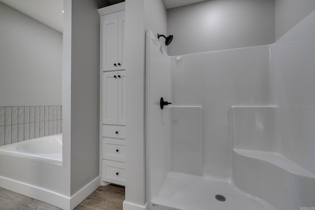 bathroom featuring wood-type flooring and shower with separate bathtub