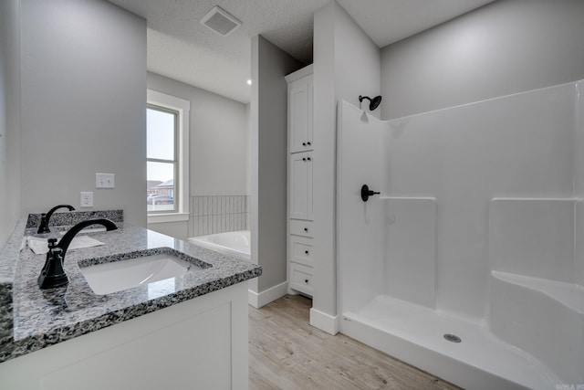 bathroom featuring hardwood / wood-style flooring, vanity, independent shower and bath, and a textured ceiling