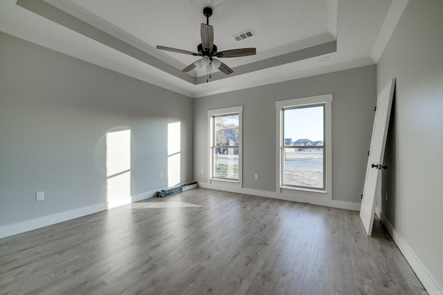 unfurnished room featuring ceiling fan, a tray ceiling, a textured ceiling, and light wood-type flooring