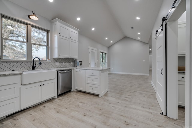 kitchen with dishwasher, sink, white cabinets, kitchen peninsula, and a barn door