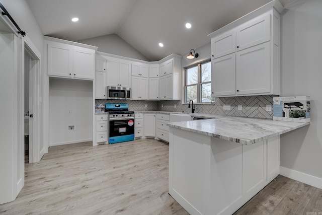 kitchen with stainless steel appliances, tasteful backsplash, lofted ceiling, and white cabinets